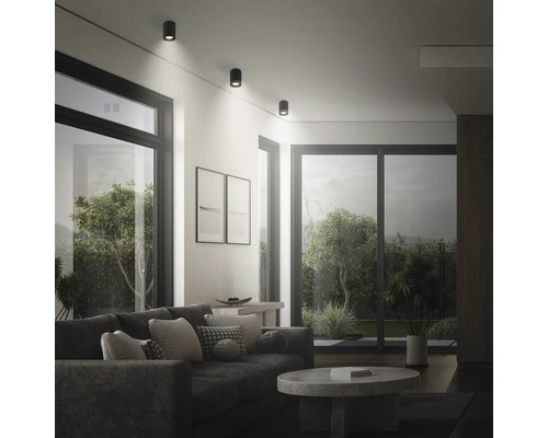 Modernes Wohnzimmer mit runden Deckenstrahlern, die für eine helle und punktuelle Beleuchtung sorgen, mit Sofa und Couchtisch.