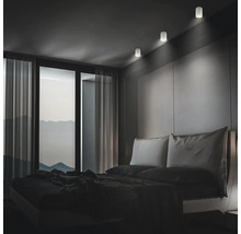 Modernes Schlafzimmer mit drei zylindrischen LED Deckenstrahlern, die für eine dezente Akzentbeleuchtung an der Wand über dem Bett sorgen.
