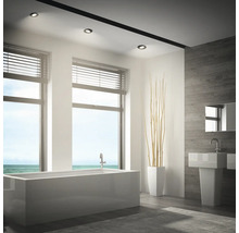 Modernes Badezimmer mit freistehender Badewanne, Waschbecken und Einbaustrahlern an der Decke bei Tageslicht mit Meerblick.