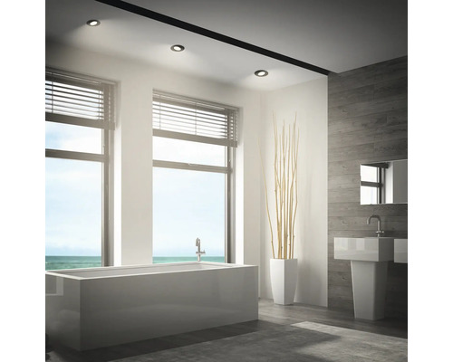 Modernes Badezimmer mit freistehender Badewanne, Waschbecken und Einbaustrahlern an der Decke bei Tageslicht mit Meerblick.