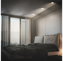 Modernes Schlafzimmer mit Einbaustrahlern in der Decke, großem Fenster mit Vorhängen und einem Doppelbett.