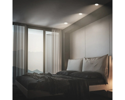 Modernes Schlafzimmer mit Einbaustrahlern in der Decke, großem Fenster mit Vorhängen und einem Doppelbett.