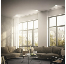 Helles Wohnzimmer mit zwei Sofas und runden Einbaustrahlern in der Decke für eine gleichmäßige Raumbeleuchtung.
