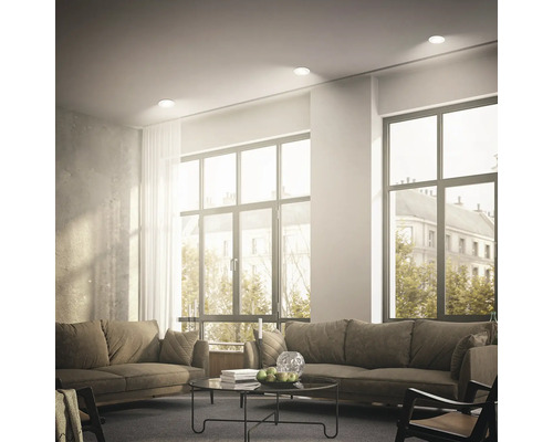 Helles Wohnzimmer mit zwei Sofas und runden Einbaustrahlern in der Decke für eine gleichmäßige Raumbeleuchtung.