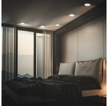 Modernes Schlafzimmer mit Einbauleuchten an der Decke, bodentiefen Fenstern und einem Doppelbett in einem minimalistischen Einrichtungsstil.