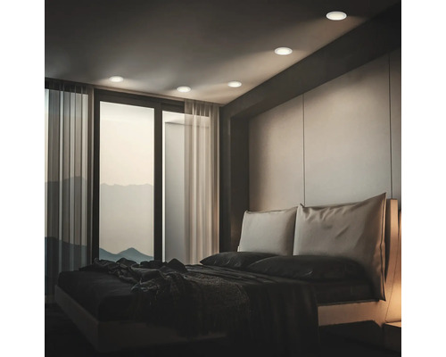 Modernes Schlafzimmer mit Einbauleuchten an der Decke, bodentiefen Fenstern und einem Doppelbett in einem minimalistischen Einrichtungsstil.