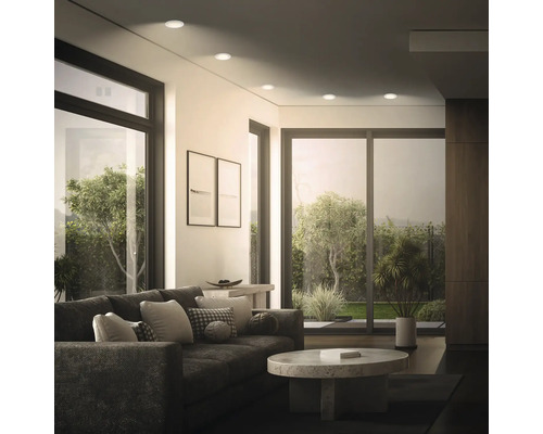 Modernes Wohnzimmer mit Einbaustrahlen in der Decke, bodentiefen Fenstern und Blick auf den Garten, stilvolle Inneneinrichtung.