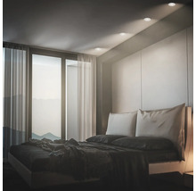 Modernes Schlafzimmer mit Einbaustrahlern an der Decke und Blick auf eine Berglandschaft durch bodentiefe Fenster.