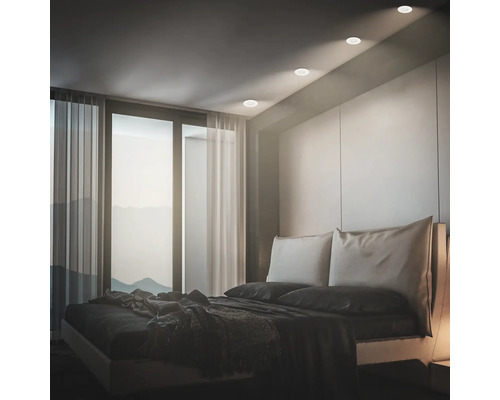 Modernes Schlafzimmer mit Einbaustrahlern in der Decke die ein warmes Licht auf das Bett werfen und eine stimmungsvolle Atmosphäre schaffen.