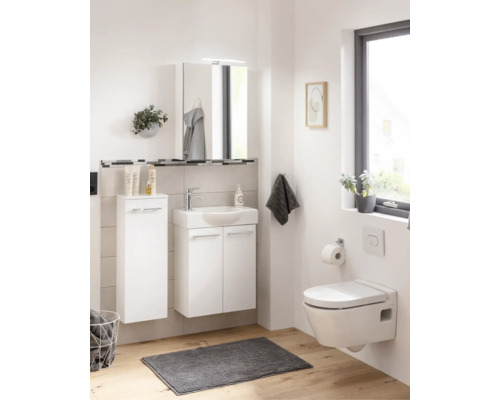 Modernes, helles Badezimmer-Set mit weißem Waschbeckenunterschrank, Spiegelschrank, Hochschrank und wandhängendem WC auf Holzoptik-Boden.
