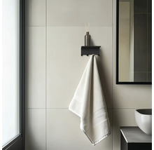 Modernes Badezimmer mit schwarzer Wandablage inklusive Haken, einem Diffusor und einem Handtuch auf großformatigen Wandfliesen.