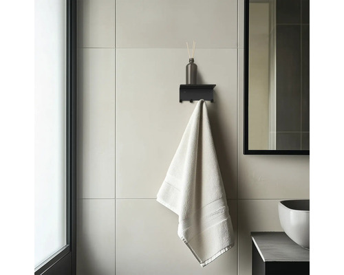 Modernes Badezimmer mit schwarzer Wandablage inklusive Haken, einem Diffusor und einem Handtuch auf großformatigen Wandfliesen.