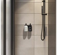Moderne Dusche mit schwarzem Seifenspender-Halter für zwei Flaschen, schwarzer Duscharmatur und großformatigen beigen Wandfliesen.
