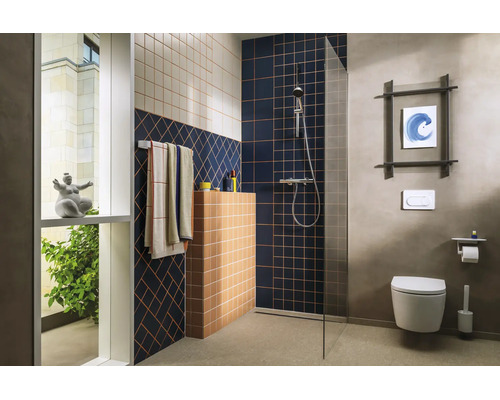 Modernes Badezimmer mit bodengleicher Dusche, Glaswand, geometrischen Fliesenmustern, wandhängender Toilette und verchromten Armaturen.