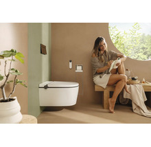 Wandhängendes Dusch-WC in einem modernen, hellen Badezimmer mit einer Frau auf einer Holzbank und minimalistischer Einrichtung.