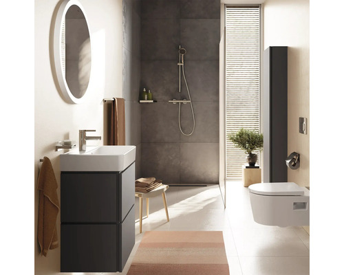 Modernes Badezimmer mit dunkelgrauem Waschtisch, weißem Waschbecken, rundem Spiegel, begehbarer Dusche und wandhängendem WC. Hell und organisiert.
