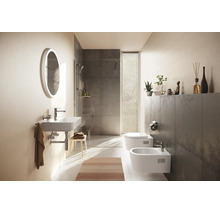 Modernes Badezimmer mit wandhängendem Waschbecken, ovalem Lichtspiegel, begehbarer Dusche mit grauen Fliesen, wandhängendem WC und Bidet.