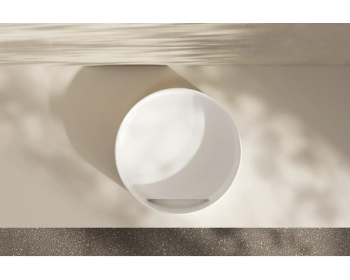 Draufsicht auf ein rundes weißes Waschbecken in einem modernen hellen Badezimmer mit weichem Lichteinfall und Schatten.