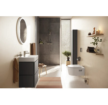 Modernes Badezimmer mit Waschtisch, rundem beleuchtetem Spiegel, begehbarer Dusche und Wandtoilette in hellem, strukturiertem Design aus Keramik.