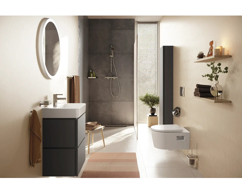 Modernes Badezimmer mit Waschtisch, rundem beleuchtetem Spiegel, begehbarer Dusche und Wandtoilette in hellem, strukturiertem Design aus Keramik.