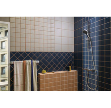 Modernes Badezimmer mit gemusterten Wandfliesen in Blau, Beige und Terrakotta, einem Handtuchhalter und einer verchromten Duscharmatur.