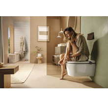Modernes, helles Badezimmer mit wandhängendem WC, minimalistischen Möbeln und Dekoration in natürlichen Erdtönen.