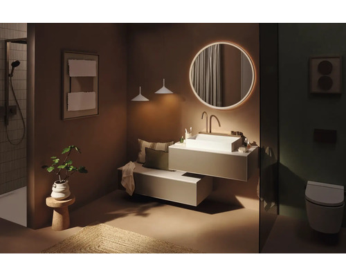 Modernes Badezimmer mit rundem, beleuchtetem Spiegel, weißem Aufsatzwaschbecken auf einem hängenden Waschtisch, Duschbereich und Wand-WC.