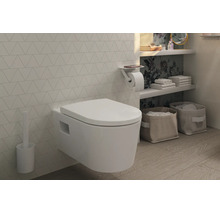 Modernes, wandhängendes WC mit Deckel, Toilettenbürste und Papierhalter mit Ablage in einem hellen Badezimmer mit Fliesen in Dreiecksoptik.