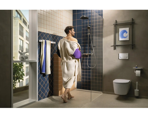 Modernes Badezimmer mit Person im Bademantel, bodengleicher Dusche, Glastrennwand, Regenduschkopf, Wand-WC, Handtuchhalter und großem Fenster.