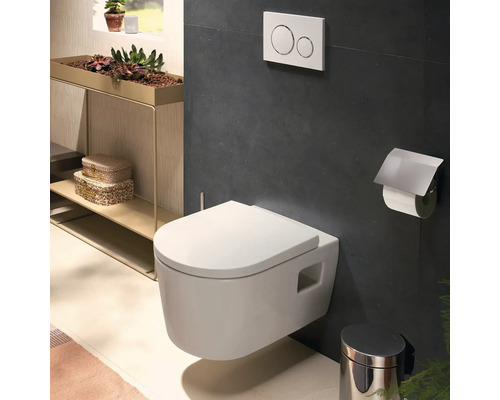 Modernes Wand-WC im Badezimmer mit Drückerplatte, Toilettenpapierhalter und Abfalleimer vor dunklen Wandfliesen.