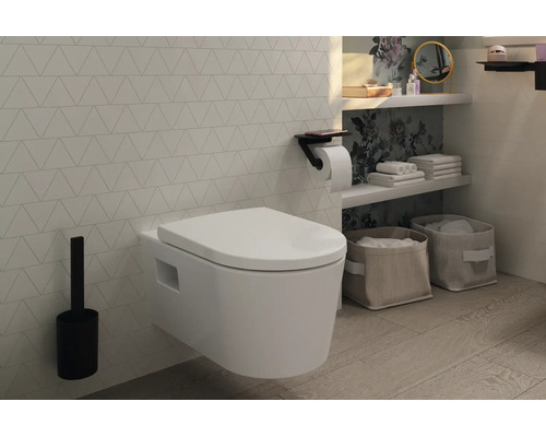 Modernes Badezimmer mit weißem wandhängendem WC, schwarzer WC-Bürstengarnitur und schwarzem Toilettenpapierhalter vor einer gemusterten Wand.
