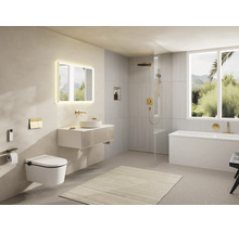 Modernes, helles Badezimmer mit Hänge-WC, Waschtisch, beleuchtetem Spiegel, begehbarer Dusche und Badewanne mit goldfarbenen Armaturen.