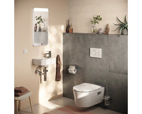 Moderne Gästetoilette mit wandhängender Toilette, kleinem Waschbecken, beleuchtetem Spiegel und dunkelgrauen Wandfliesen.