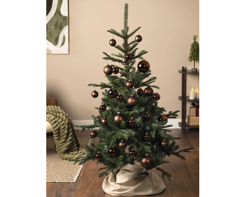 Geschmückter Weihnachtsbaum in einem hellen Wohnzimmer mit braunen Christbaumkugeln in verschiedenen Größen, matten und glänzenden Oberflächen.
