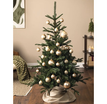 Dekorierter Weihnachtsbaum mit goldenen Kugeln und einer beigen Baumdecke in einem gemütlichen Wohnzimmer.