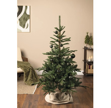 Ein geschmückter Weihnachtsbaum in einem hellen Wohnzimmer mit Parkettboden. Der Baum ist mit gemusterten Kugeln verziert.
