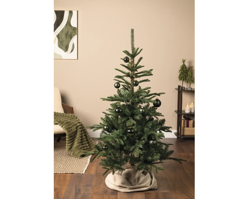 Ein geschmückter Weihnachtsbaum in einem hellen Wohnzimmer mit Parkettboden. Der Baum ist mit gemusterten Kugeln verziert.