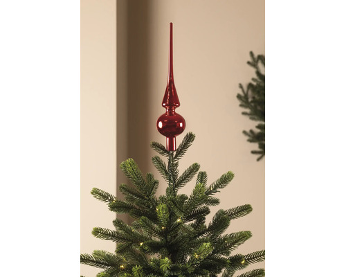 Rote, glänzende Christbaumspitze auf einem grünen Weihnachtsbaum mit kleinen Lichtern.
