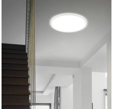 Flache runde LED-Deckenleuchte montiert in einem modernen hellen Treppenhaus mit Holzstufen.