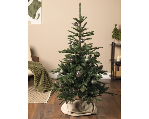Künstlicher Weihnachtsbaum mit gemusterten Kugeln in einem gemütlich eingerichteten Wohnzimmer mit Holzboden und Weihnachtsdekoration.