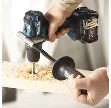 Makita Akku-Bohrschrauber 40 Volt bohrt mit Zusatzhandgriff ein Loch in ein Holzbrett, wobei Holzspäne entstehen.