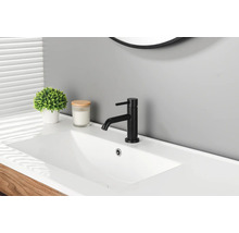 Moderne schwarze Waschtischarmatur auf einem weißen Waschbecken in einem hellen Badezimmer mit Pflanze und Kerze.