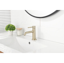 Moderner Einhebel-Waschtischmischer in mattem Gold auf einem weißen Keramikwaschbecken in einem hellen Badezimmer.