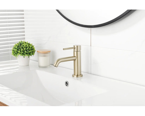 Moderner Einhebel-Waschtischmischer in mattem Gold auf einem weißen Keramikwaschbecken in einem hellen Badezimmer.