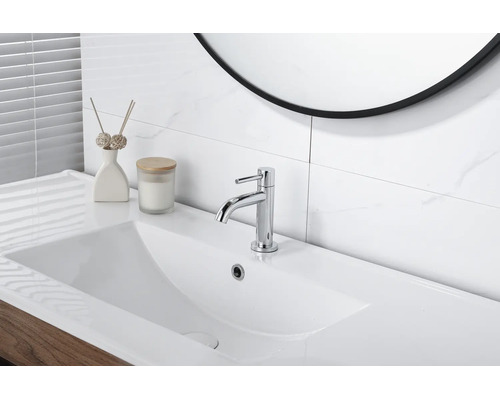 Moderne Waschtischarmatur in Chrom auf einem weißen Waschbecken in einem hellen Badezimmer mit Fliesen in Marmoroptik.