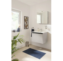 Modernes Badezimmer mit weißem Hängewaschbeckenunterschrank, Spiegelschrank, Armatur und blauem Badteppich in hellem Ambiente.