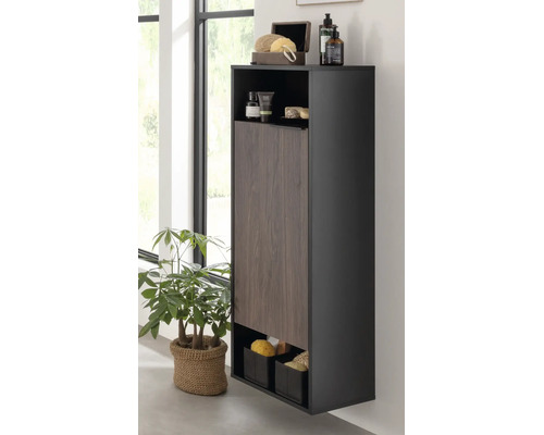 Moderner Badezimmer-Hochschrank mit dunklem Korpus, einer Tür in Holzoptik sowie offenen Fächern für Pflegeprodukte und Zubehör.