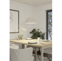 Helle Esszimmer-Szene mit einer halbrunden Pendelleuchte über einem Holztisch, dekoriert mit Geschirr, einer Vase und Pflanzen im Hintergrund.