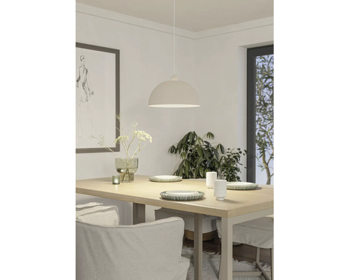 Helle Esszimmer-Szene mit einer halbrunden Pendelleuchte über einem Holztisch, dekoriert mit Geschirr, einer Vase und Pflanzen im Hintergrund.