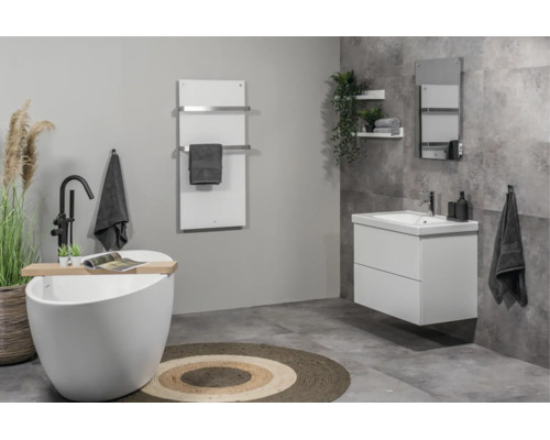 Modernes Badezimmer mit freistehender Badewanne, Waschtischunterschrank, Infrarotheizung mit Handtuchhaltern und grauen Fliesen in Steinoptik.